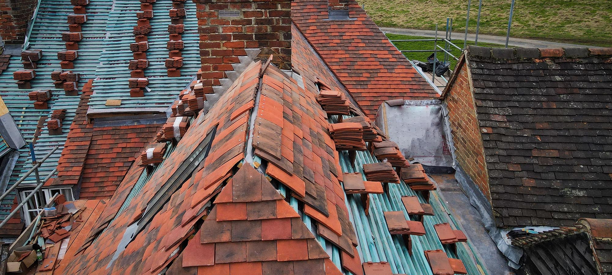 Clay tiles stacked ready to be relaid on a stripped roof